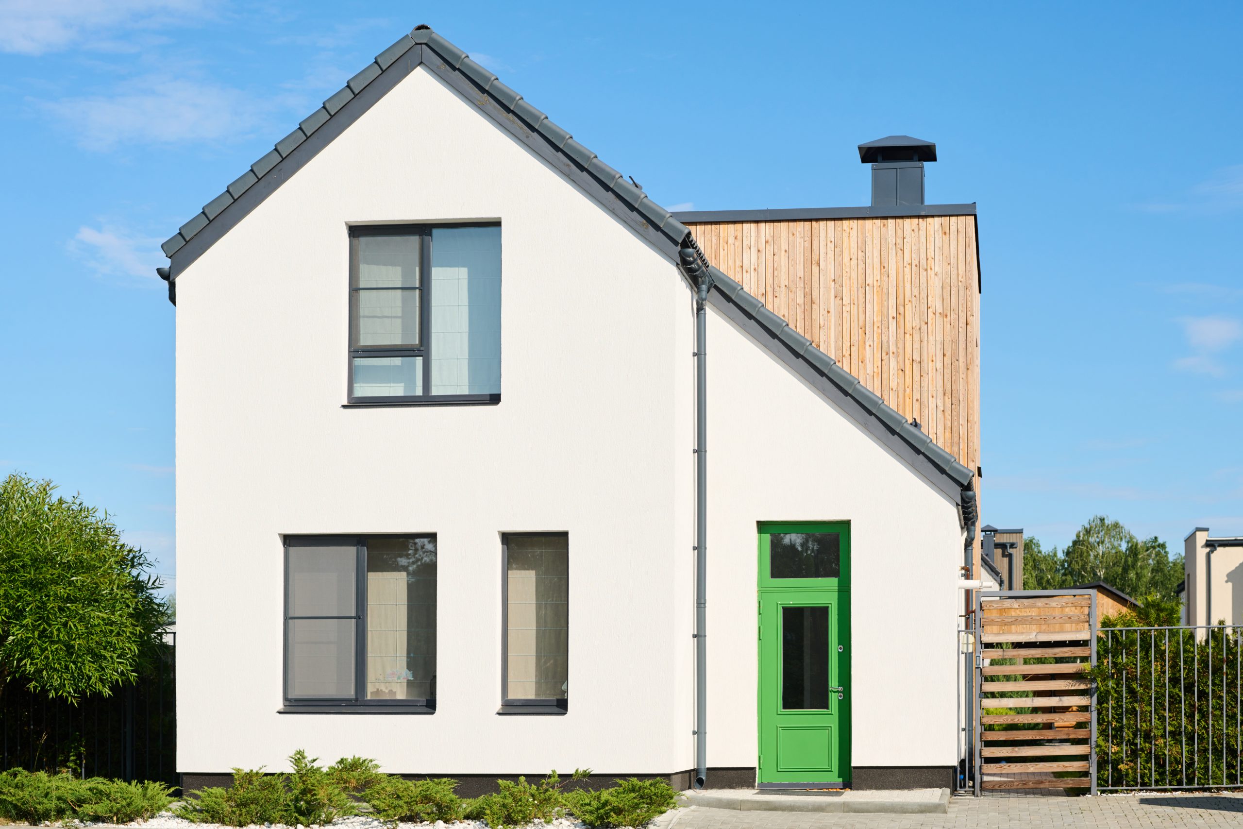 Facade of white two storey cottage surrounded by small green plants and bushes
